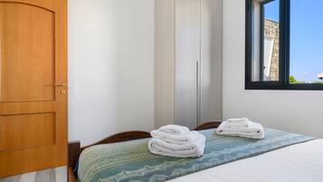 Ein Schlafzimmer mit Bett, einer Holztür, einem Kleiderschrank und einem Fenster.
