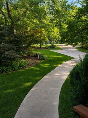A curved concrete pathway in a well-maintained garden with various shrubs and trees. - 3 bed 2 bath in Kennesaw with Game Room Near KSU and Truist Park (Kennesaw)