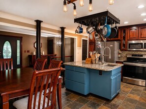 A kitchen with a blue island, stainless steel appliances, and hanging pots. - 3 bed 2 bath in Kennesaw with Game Room Near KSU and Truist Park (Kennesaw)