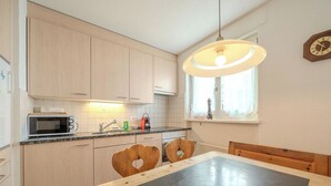 Una cocina con armarios de madera, un microondas, un lavamanos y una mesa con sillas con forma de corazón.