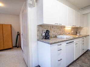 Une cuisine moderne avec des armoires blanches, un comptoir en granit et un évier en acier inoxydable.