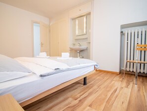 Une chambre d’hôtel avec un lit, une table de chevet, un miroir, un lavabo et un radiateur.
