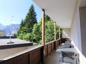 A balcony with outdoor seating, a flagpole, and a view of trees and mountains. - Haldahus 3 by Arosa Holiday Appartement/Fewo,  , 7-Bettwohnung Haldahus 3 by Interhome (Arosa)