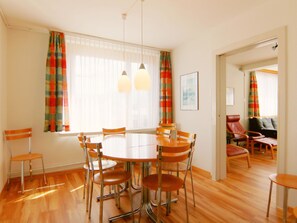 Un espace repas comprenant une table ronde, six chaises et deux lampes suspendues.