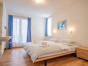 Une chambre à coucher avec un lit, des tables de chevet, une chaise et une fenêtre avec des rideaux.