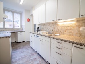 A kitchen with white cabinets, a granite countertop, a stainless steel sink, and a red clock on the wall. - Haldahus 3 by Arosa Holiday Appartement/Fewo,  , 7-Bettwohnung Haldahus 3 by Interhome (Arosa)