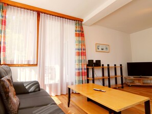 Un salon comprenant un canapé, une table basse, un téléviseur et un système audio.