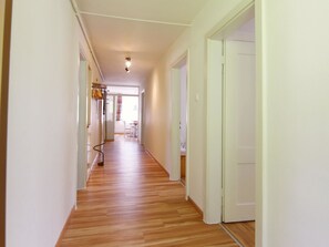 Un couloir doté d’un plancher en bois, de murs blancs et de portes donnant sur d’autres pièces.