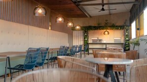 A restaurant with multiple seating areas, including tables and chairs, and a kitchen in the background. - HOTEL RILUX BARRANCABERMEJA (Barrancabermeja)