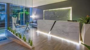 A modern reception area with a marble counter, glass walls, and indoor plants. - HOTEL RILUX BARRANCABERMEJA (Barrancabermeja)
