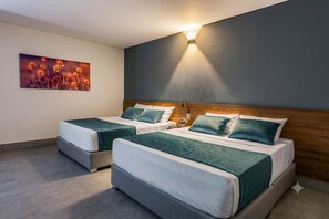 Habitación de hotel con dos camas, una mesita de noche, una lámpara de pared y un cuadro.