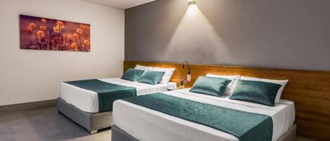 Habitación de hotel con dos camas, un cuadro en la pared y una lámpara fijada a la pared.