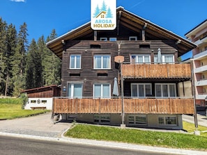 A wooden building with a balcony, a sign reading 'Arosa Holiday', and a parking area. - Schwarzsee 2 by Arosa Holiday Appartement/Fewo Schwarzsee 2 by Interhome (Arosa)