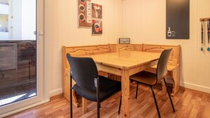 A dining area with a wooden table and chairs, a glass door entrance, and wall decorations including a coffee-themed artwork and a wine bottle illustration. - Schwarzsee 2 by Arosa Holiday Appartement/Fewo Schwarzsee 2 by Interhome (Arosa)