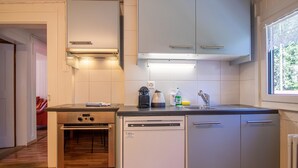 A compact kitchen with a built-in oven, dishwasher, and a small countertop. - Schwarzsee 2 by Arosa Holiday Appartement/Fewo Schwarzsee 2 by Interhome (Arosa)