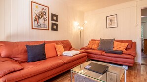 A living room with two red leather sofas, a glass coffee table, and wall-mounted light fixtures. - Schwarzsee 2 by Arosa Holiday Appartement/Fewo Schwarzsee 2 by Interhome (Arosa)