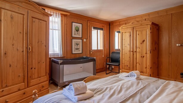 A wooden room with a bed, a chair, and a small table. - Schwarzsee 2 by Arosa Holiday Appartement/Fewo Schwarzsee 2 by Interhome (Arosa)