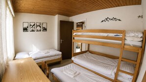 Una stanza con letti a castello, una scrivania in legno e una porta che dà su un'altra stanza.