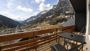 Un balcone con vista su un paesaggio montuoso, un tavolo e una sedia.
