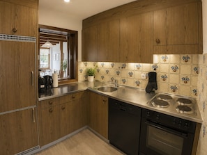 A kitchen with wooden cabinets, a stainless steel sink, a stove, and a dishwasher. - Residenz Clabina Leukerbad # 6-bed apartment, Bad, WC by Interhome (Leukerbad)