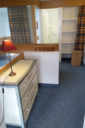 A room with a desk, a lamp, a dresser, a shelf, and a small stool. - Fortuna 317 # 6-bed apartment, Dusche, WC 6-Bettwohnung, Dusche, WC by Interhome (Leukerbad)