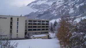 Un bâtiment portant l’inscription « FORTUNA », entouré de montagnes enneigées.