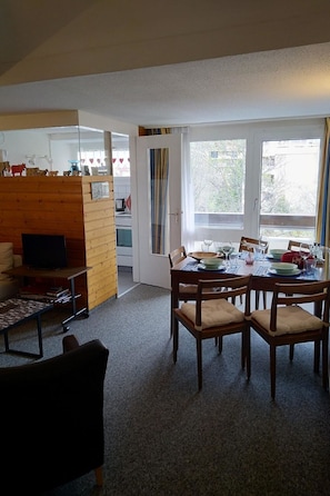 A dining area with a table set for four, a television in the corner, and a view of the outdoors through a window. - Fortuna 317 # 6-bed apartment, Dusche, WC 6-Bettwohnung, Dusche, WC by Interhome (Leukerbad)