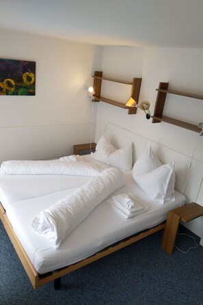 A double bed with white bedding, a wooden headboard, and two bedside tables with lamps. - Fortuna 317 # 6-bed apartment, Dusche, WC 6-Bettwohnung, Dusche, WC by Interhome (Leukerbad)
