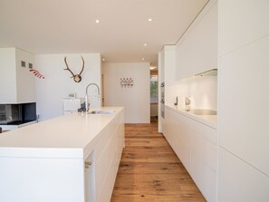 A modern kitchen with a central island, wooden flooring, and decorative wall art. - PlantA rosa by Arosa Holiday Appartement/Fewo, Dusche oder Bad, WC, 6-Bettwohnun by Interhome (Arosa)