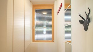 Un couloir doté d’un plancher en bois, d’une fenêtre avec des stores, d’une porte et d’une décoration murale représentant une tête de cerf.
