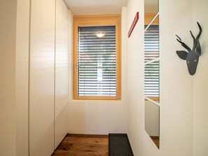 A hallway with a wooden floor, a window with blinds, a door, and a wall-mounted deer head decoration. - PlantA rosa by Arosa Holiday Appartement/Fewo, Dusche oder Bad, WC, 6-Bettwohnun by Interhome (Arosa)
