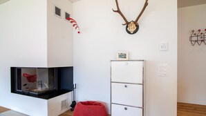 Une chambre moderne avec une cheminée, un fauteuil en forme de sac de haricots rouge, un meuble blanc et des éléments de décoration murale, notamment des bois de cerf et un crâne.