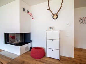 A modern room with a fireplace, a red bean bag, a white cabinet, and wall decorations including antlers and a skull. - PlantA rosa by Arosa Holiday Appartement/Fewo, Dusche oder Bad, WC, 6-Bettwohnun by Interhome (Arosa)