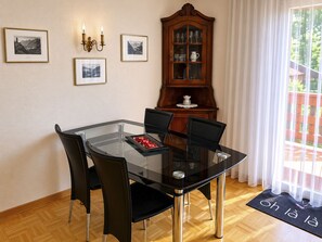 A dining area with a glass table, black chairs, a wooden cabinet, and framed pictures on the wall. - Majesta Leukerbad # 2-bed apartment, Bad, WC by Interhome (Leukerbad)