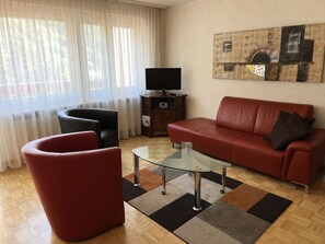 A living room with a sofa, armchair, and glass coffee table. - Majesta Leukerbad # 2-bed apartment, Bad, WC by Interhome (Leukerbad)