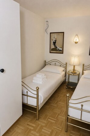 A hotel room with two beds, a bedside lamp, a framed picture on the wall, and a wooden floor. - Majesta Leukerbad # 2-bed apartment, Bad, WC by Interhome (Leukerbad)