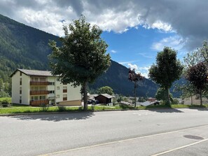 A building with balconies, a parking lot, and a mountain backdrop. - Majesta Leukerbad # 2-bed apartment, Bad, WC by Interhome (Leukerbad)