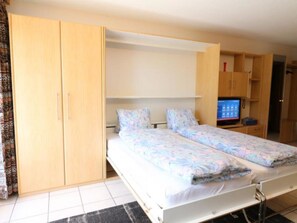 A bedroom with a bed, two bedside tables, a wardrobe, and a television. - Adlerhorst Leukerbad # 2-bed apartment, Dusche, WC by Interhome (Leukerbad)