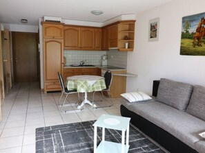 Ett kompakt bostadsutrymme med ett litet kök, en matplats och en soffa.