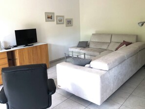 Un salon moderne avec un canapé, un téléviseur et un bureau.