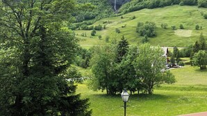 A mountainous landscape with a waterfall, lush greenery, and a wooden deck. - Edelweiss D 02 # 4-bed apartment, Dusche, WC 4-Bettwohnung, Dusche, WC by Interhome (Leukerbad)