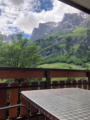 A table and chairs in a room with a mountain view. - Edelweiss D 02 # 4-bed apartment, Dusche, WC 4-Bettwohnung, Dusche, WC by Interhome (Leukerbad)