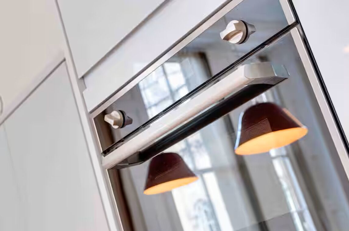 Una cocina moderna con horno empotrado y dos lámparas colgantes.