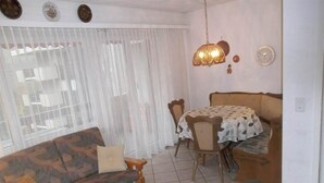 Una sala de estar con sofá, una mesa de comedor con sillas y un tapete estampado.