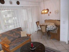 Ein Wohnzimmer mit einer Couch, einem Esstisch mit Stühlen und einem gemusterten Teppich.