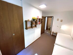 Ein Hotelzimmer mit Schrank, Nachttisch, einer kleinen Ablage mit Dekoration und einer Tür zu einem weiteren Raum.
