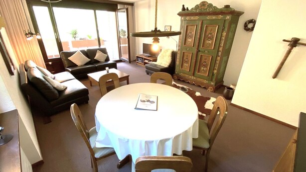 A dining area with a round table, chairs, a sofa, and a cabinet. - Lärchenwald 1803 # 5-bed apartment, Bad, WC 5-Bettwohnung, Bad, WC by Interhome (Leukerbad)