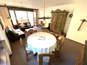 Een eethoek met een ronde tafel, stoelen, een bank en een kast.