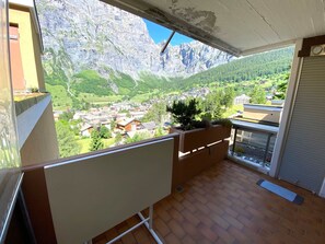 A balcony with a view of a mountainous landscape, a whiteboard, and a closed shutter. - Lärchenwald 1803 # 5-bed apartment, Bad, WC 5-Bettwohnung, Bad, WC by Interhome (Leukerbad)