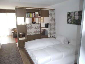 A bedroom with a bed, a wardrobe, a desk, and a chair. - Valère Leukerbad # 2-bed apartment, Dusche, WC by Interhome (Leukerbad)